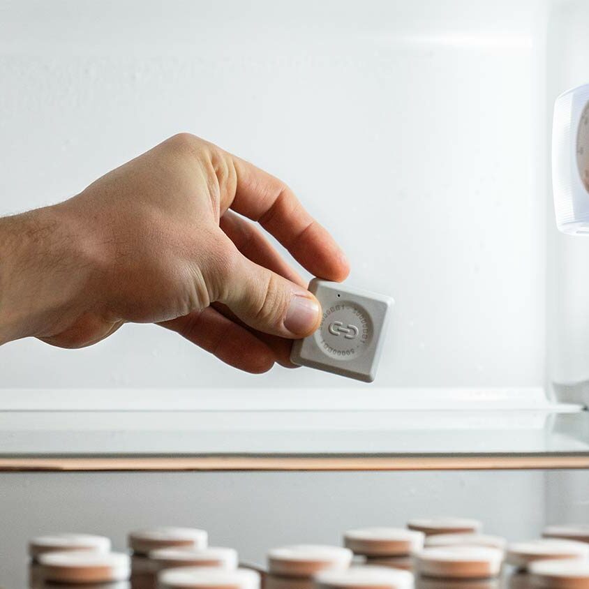 Temperaturüberwachung Kühlschrank: Das Bild zeigt eine Person, welche einen Sensor in einen geöffneten Medikamenten Kühlschrank einlegt.